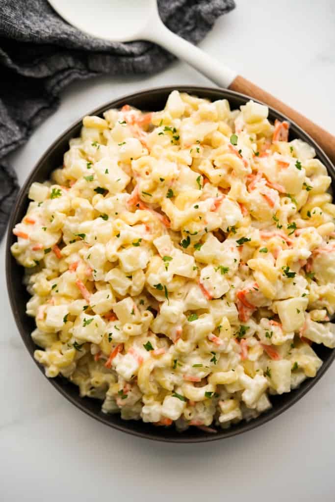 Top down view of a bowl of potato and macaroni salad with shredded carrots