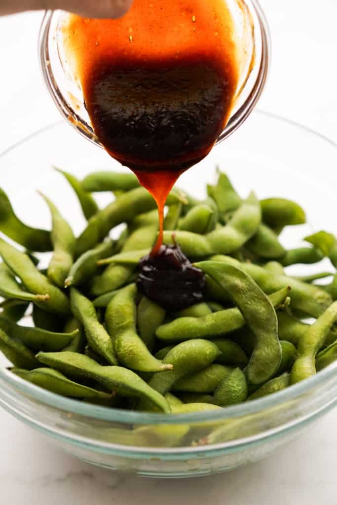 Pouring garlic hoisin sauce onto edamame