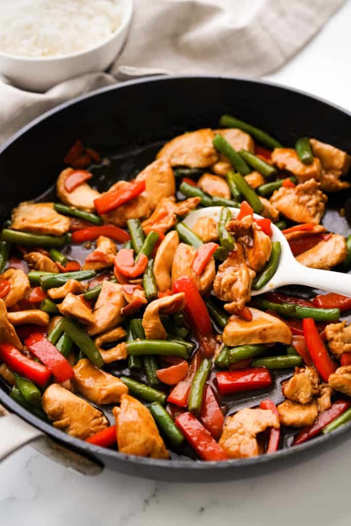 A large skillet loaded with teriyaki chicken stir fry with veggies