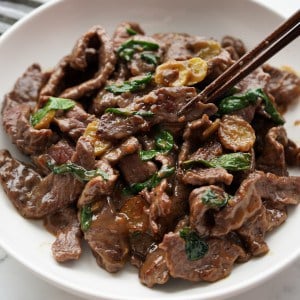 Digging into a plate of stir fry beef with ginger slices and green onions