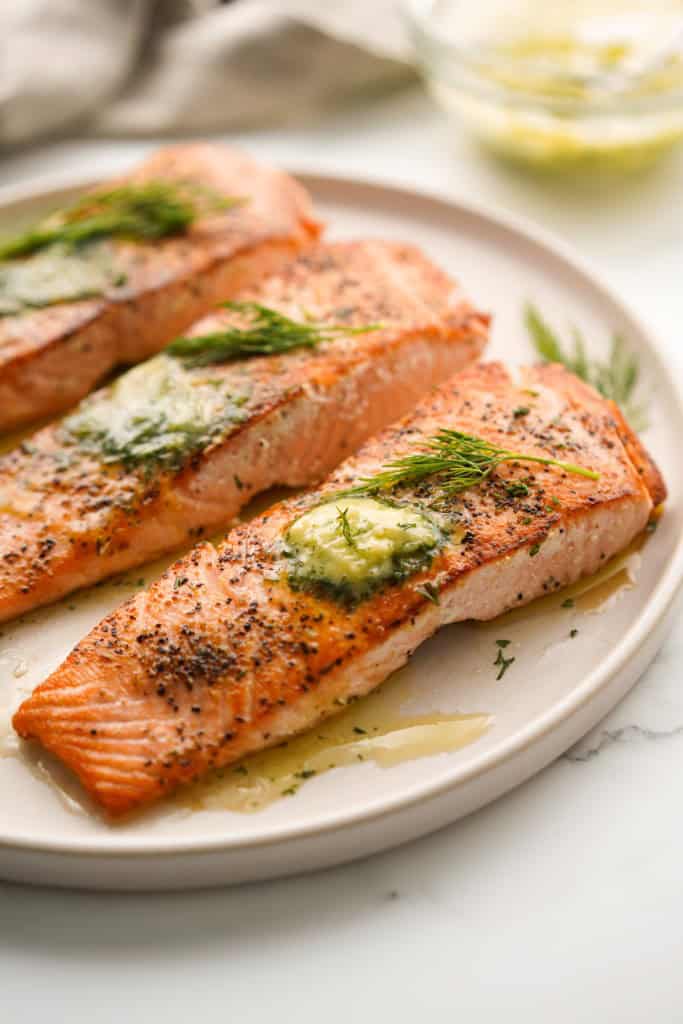 Slices of salmon pan seared and topped dollops of with dill butter