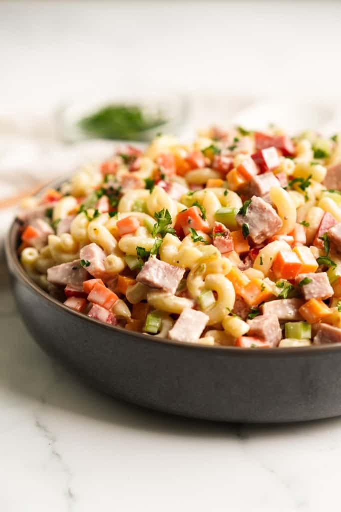 Closeup of a bowl of macaroni pasta salad tossed with ham and veggies