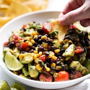 Dipping a chip into a bowl of avocado black bean salsa