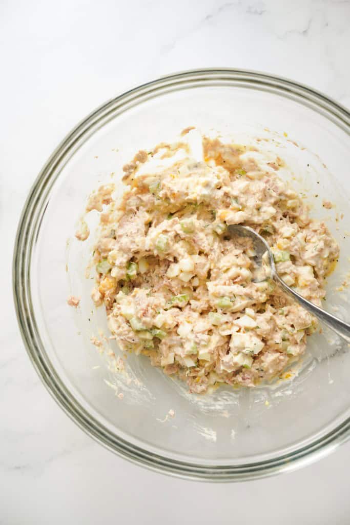 tuna and egg salad mixed together in mayo dressing in a large mixing bowl