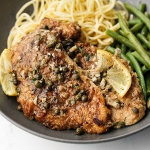 Lemon chicken piccata topped with capers served with green beans and spaghetti