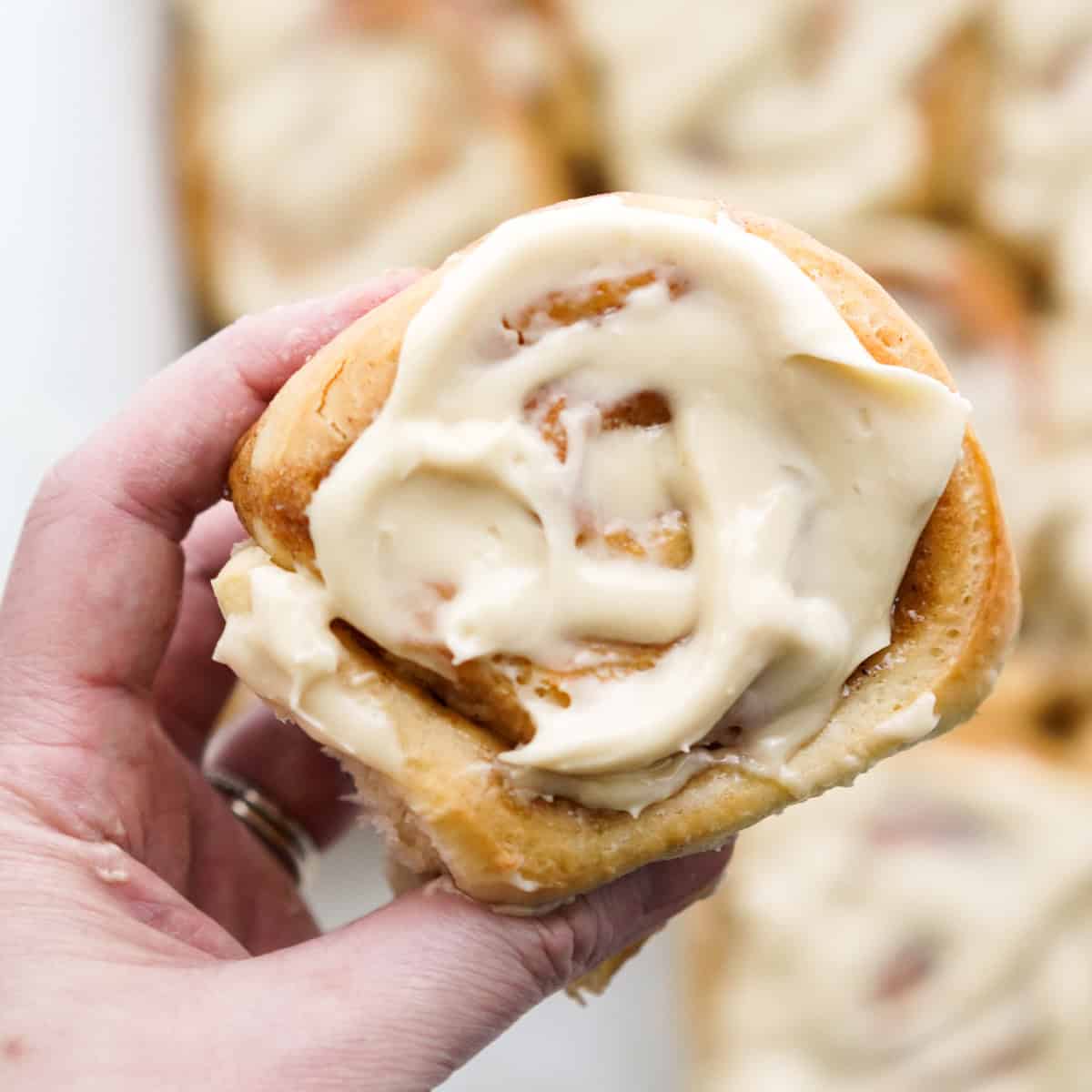 Hand holding a honey bun topped with honey icing