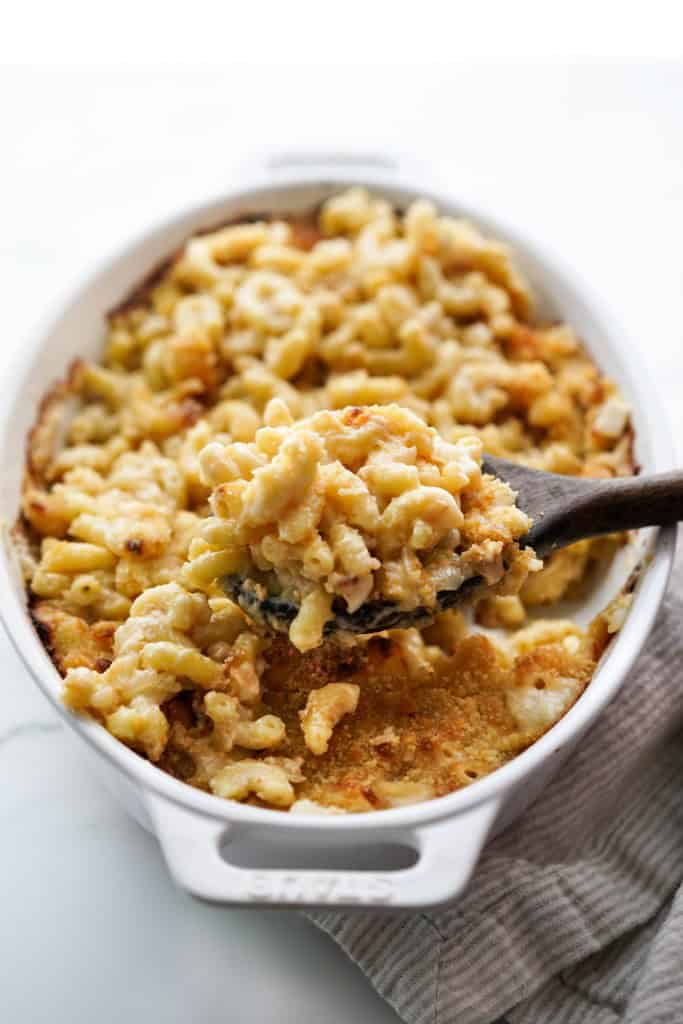 Using a wooden spoon to scoop a large scoop of french onion mac and cheese