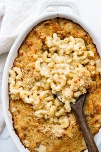 Scooping out gooey mac and cheese from a baked casserole