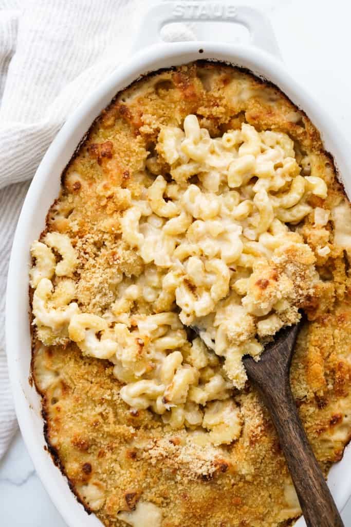 Scooping out gooey mac and cheese from a baked casserole