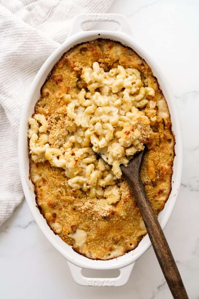Digging into an oval casserole of French onion mac and cheese topped with breadcrumbs