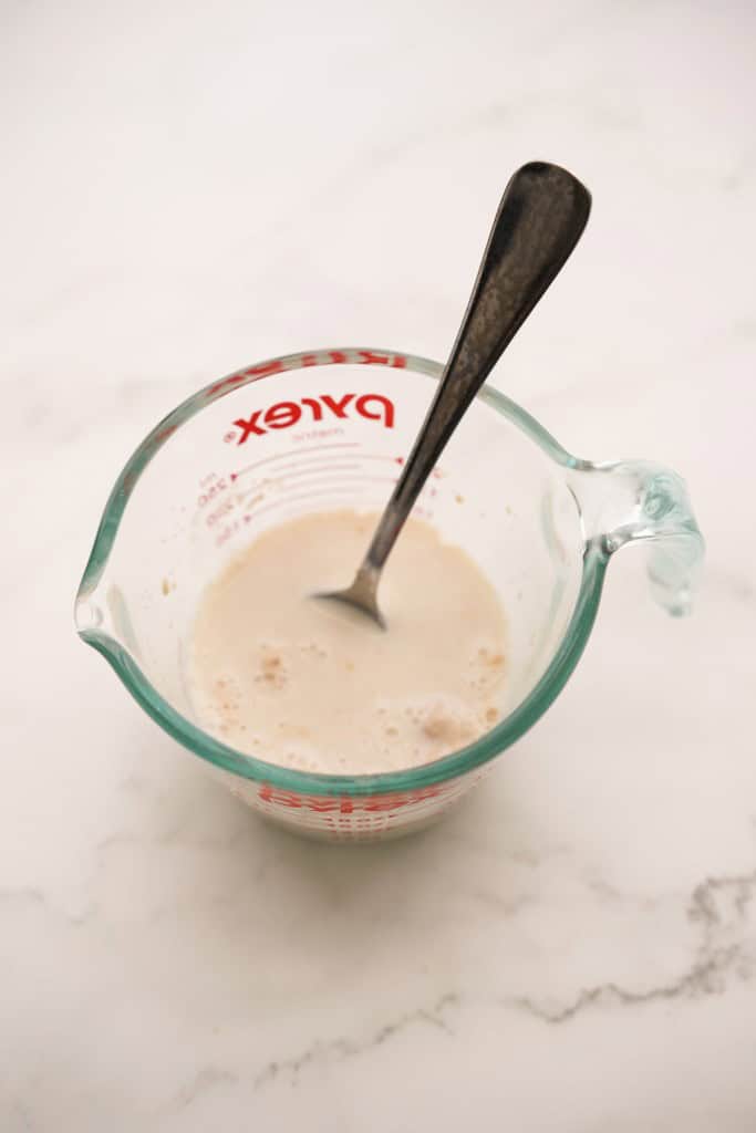 Foamy milk and yeast mixture in a measuring cup