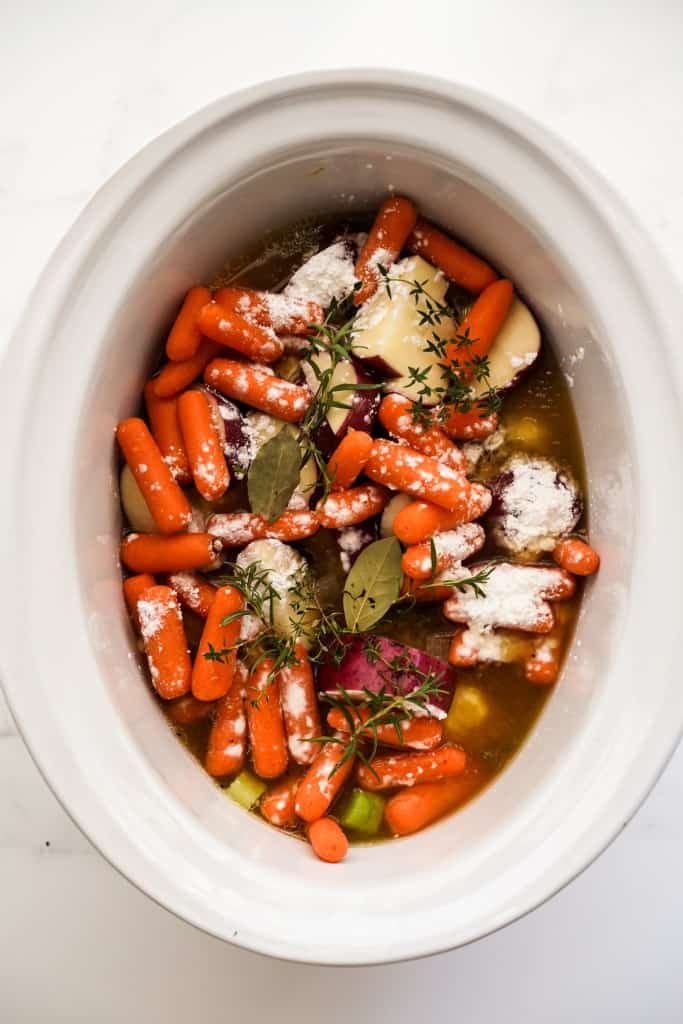 Carrots, potatoes, chicken, broth and fresh herbs in a crockpot