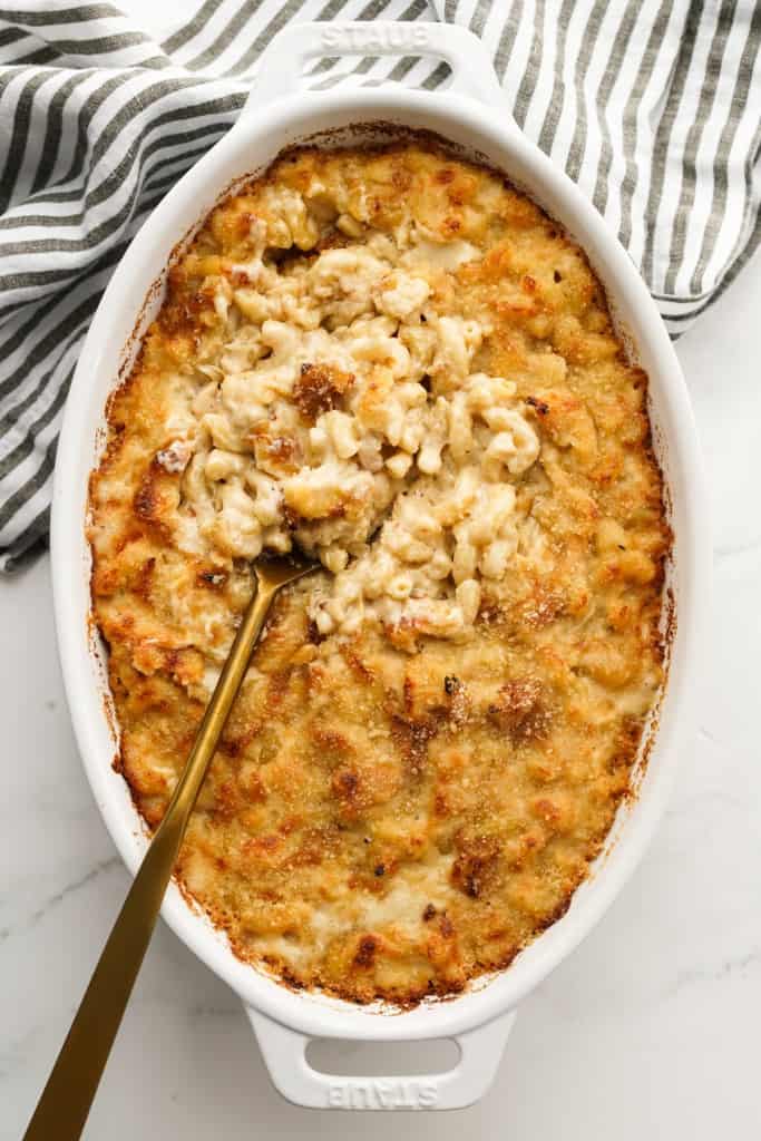 Top down view of a oval casserole dish with a baked French onion mac and cheese with golden brown tops