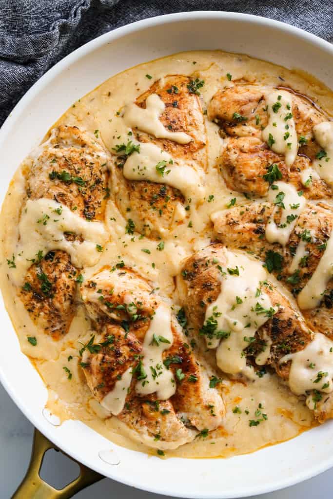 A closeup of a skillet of chicken tenderloins sitting in a creamy sauce