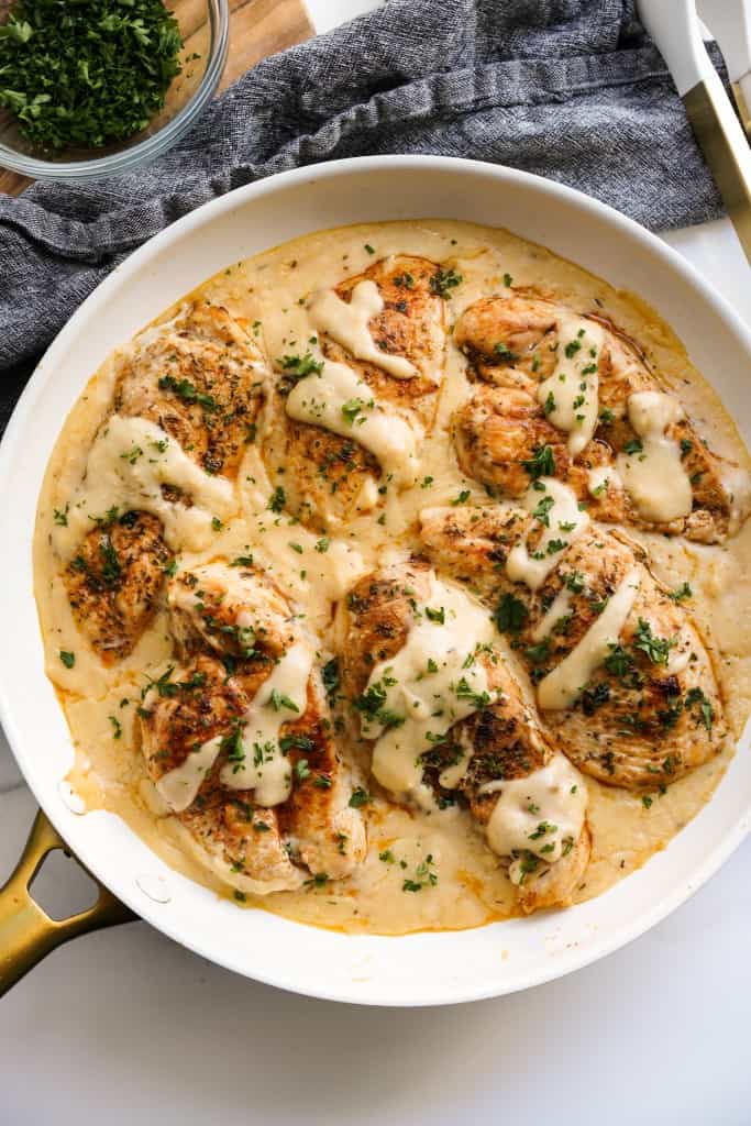 A large skillet of garlic herb chicken smothered with cream sauce