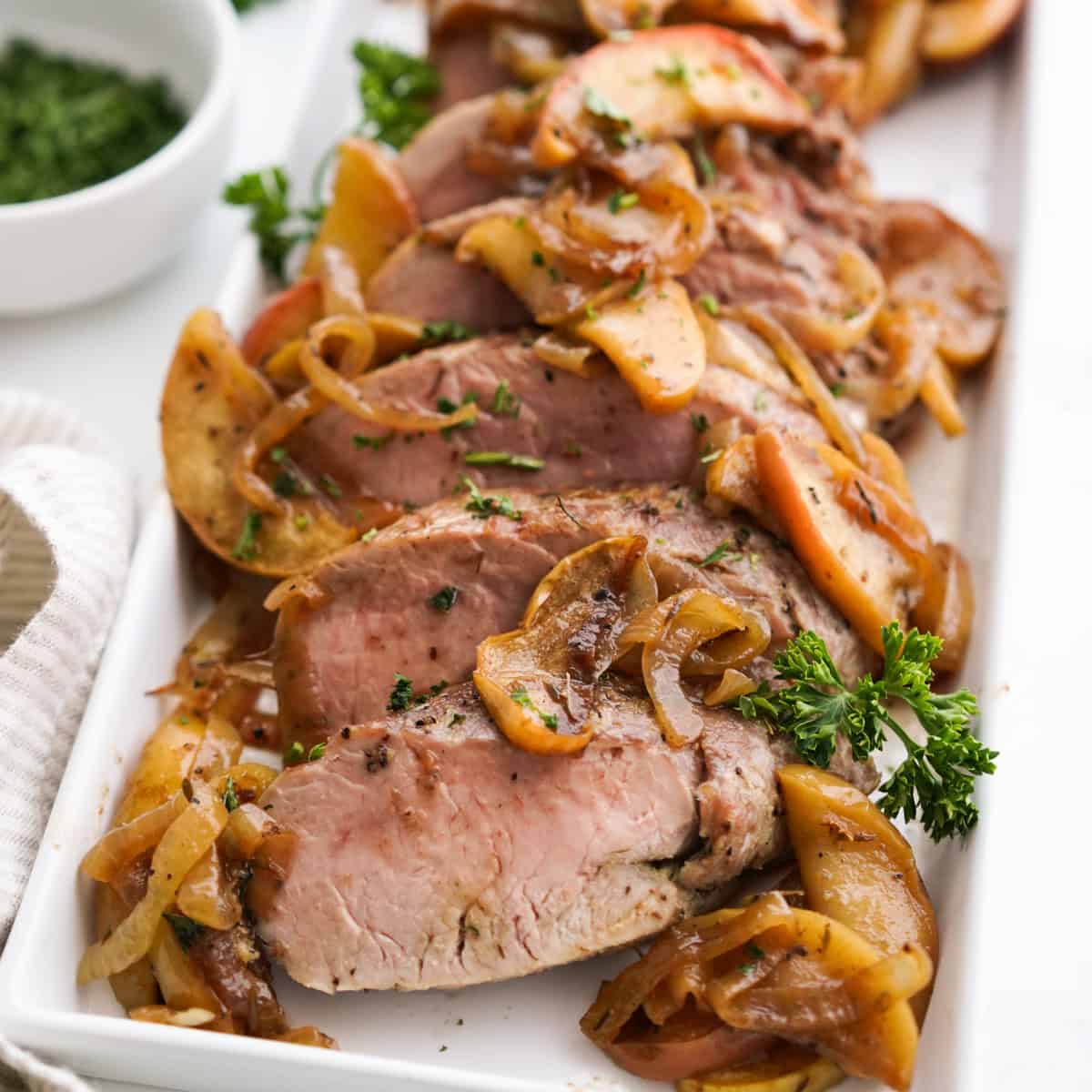 Slices of pork tenderloin with cooked apples and onions