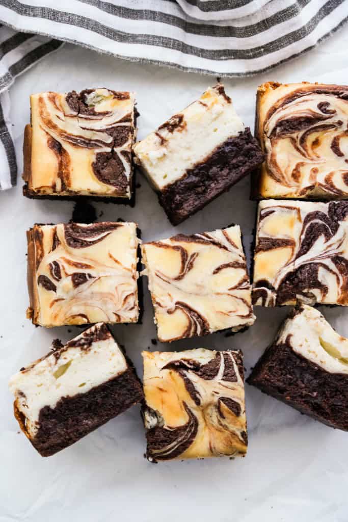 A few pieces of cheesecake brownies from the top down and some standing on the sides showing the layers of brownie at the bottom and cheesecake on top