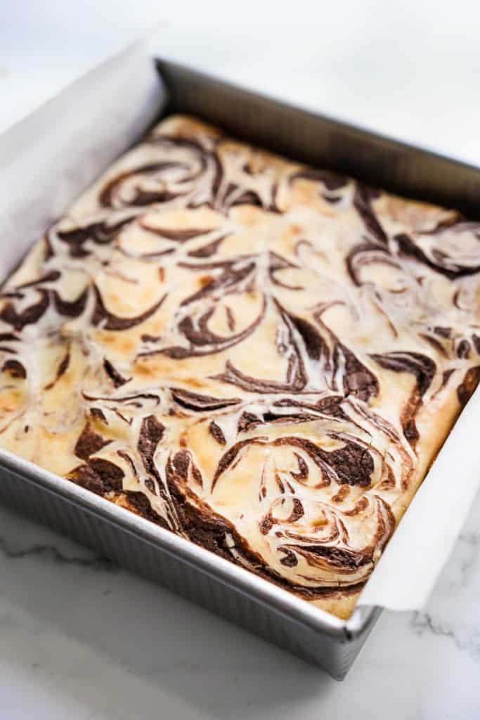 A square pan of cheesecake brownie with a marble swirl on top