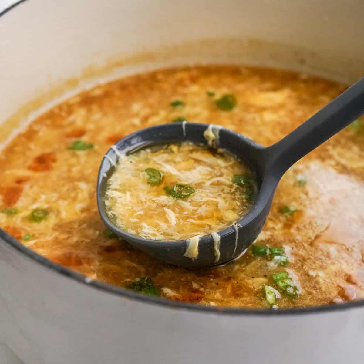 Scooping up egg drop soup from a pot with a ladle