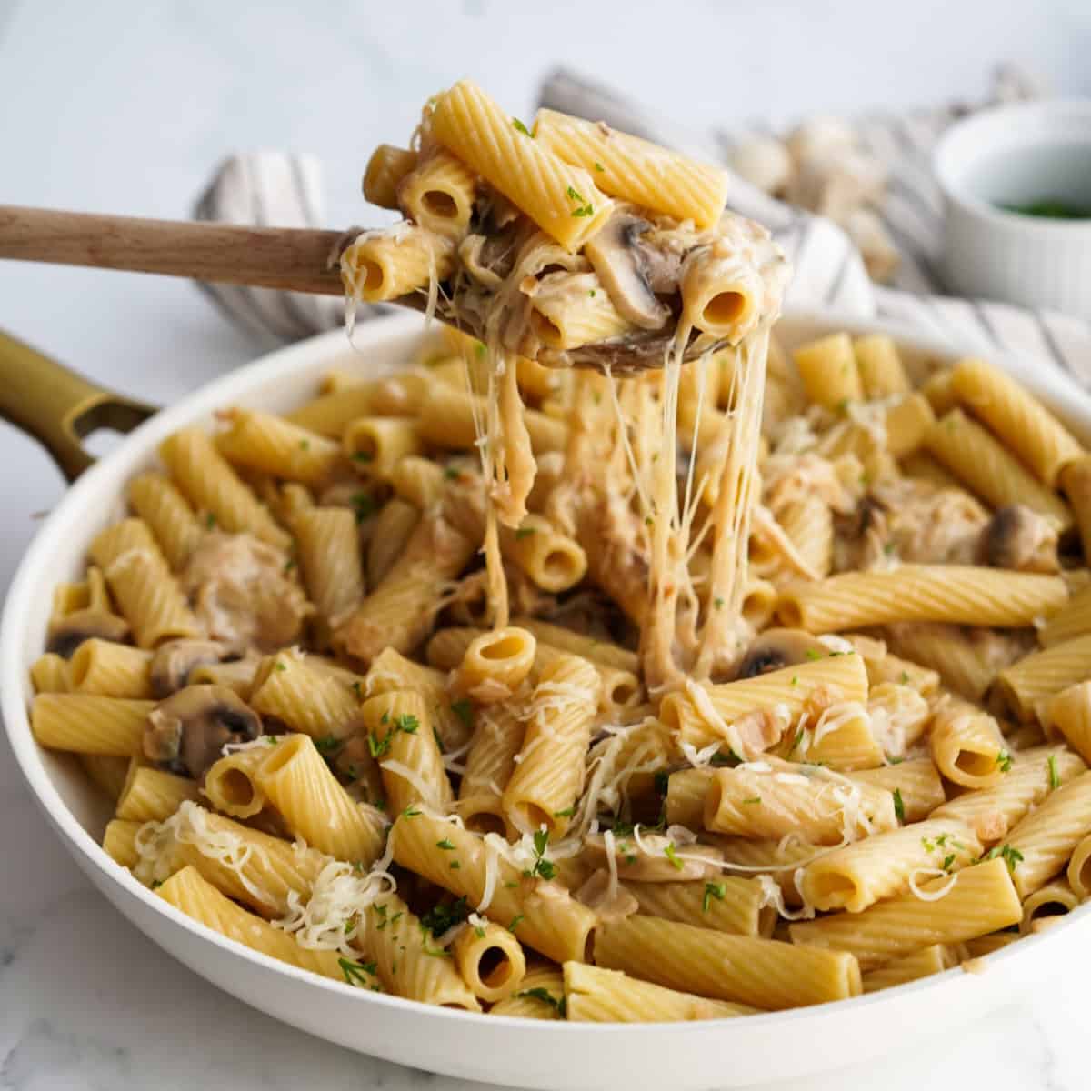 Lifting up cheesy french onion pasta from a bowl
