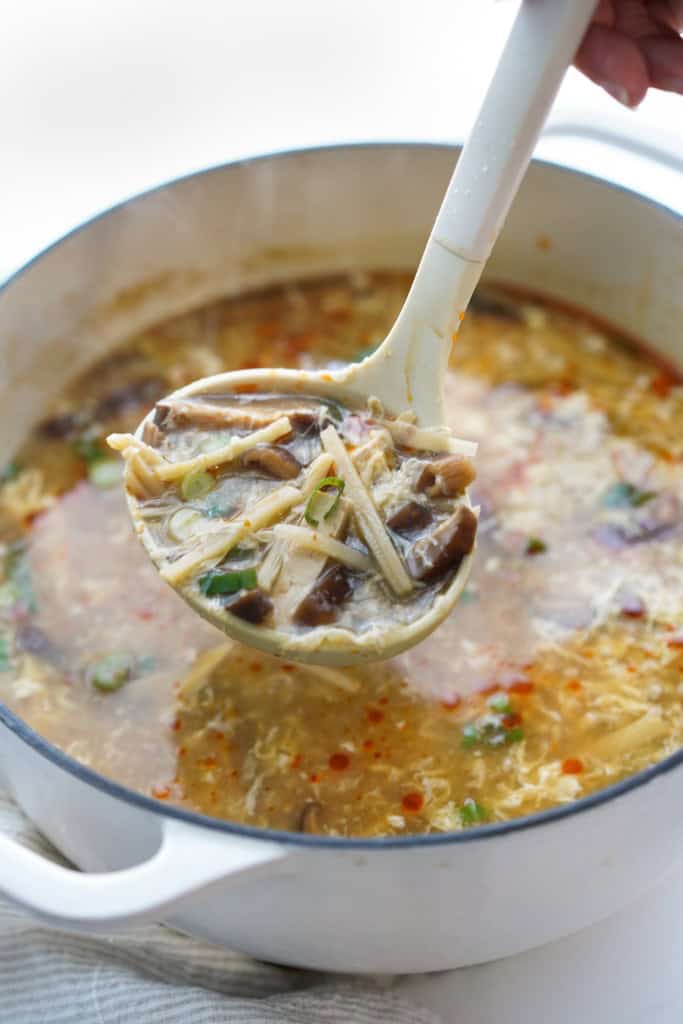 Scooping up a spoonful of tofu, bamboo shoots and mushrooms from hot and sour soup