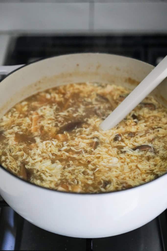 A large pot of hor and sour soup with egg strands floated to the top