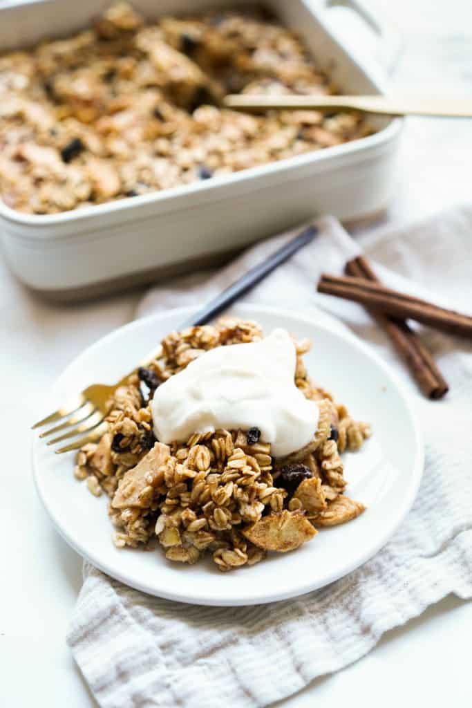 A plate of oatmeal baked with apples and raisins topped with Greek yogurt