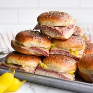 A stack of hot Italian sliders with layers of ham, salami, capocollo and cheese