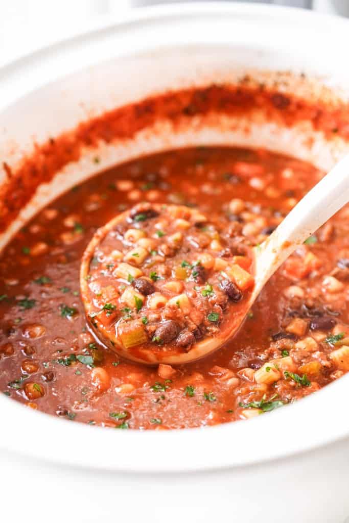Scooping up a large scoop of pasta fagioli soup with beans and ground beef