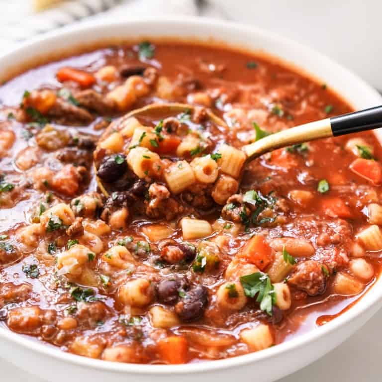 Using a spoon to dig into a bowl of pasta fagioli
