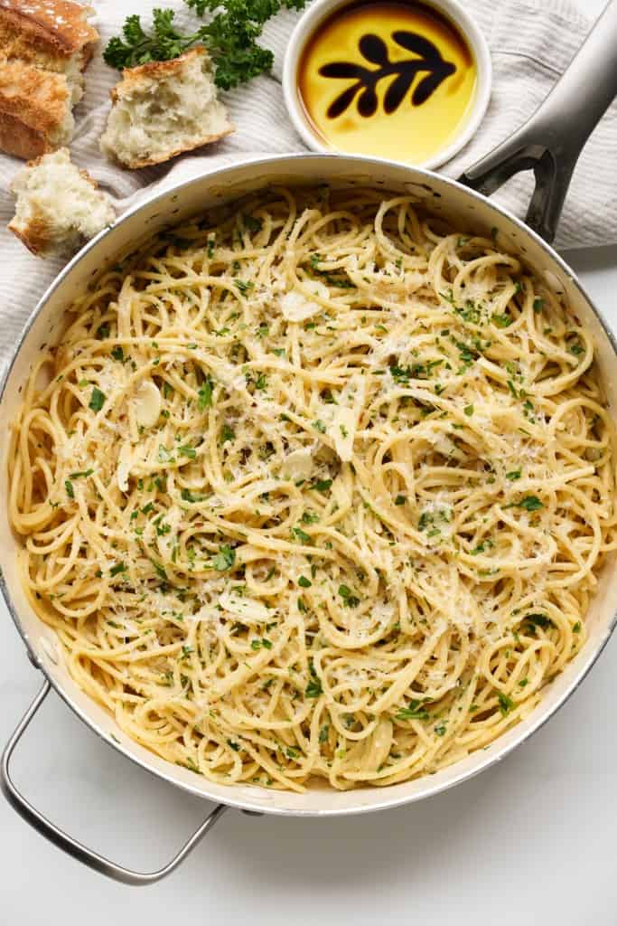 Top down view of a large skillet of spaghetti tossed in garlic and olive oil