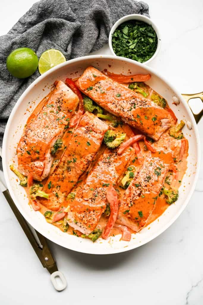 Top down view of a large skillet of Thai red curry salmon fillets