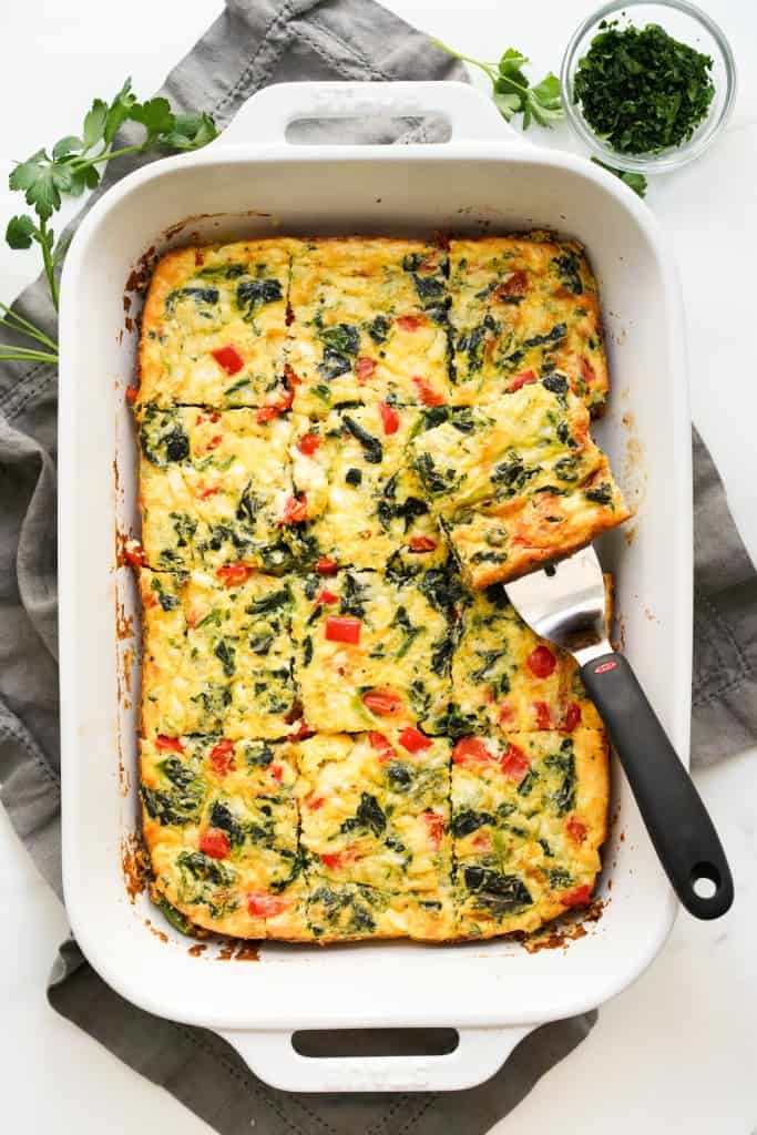 A rectangular casserole dish of egg bake made with cottage cheese, spinach, bell peppers and sausage.