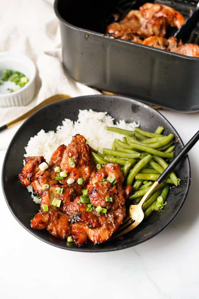 A plate of teriyaki chicken thighs served with rice and green beans