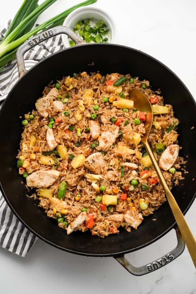 A large skillet loaded with Thai pineapple fried rice tossed with veggies, eggs and chunks of chicken
