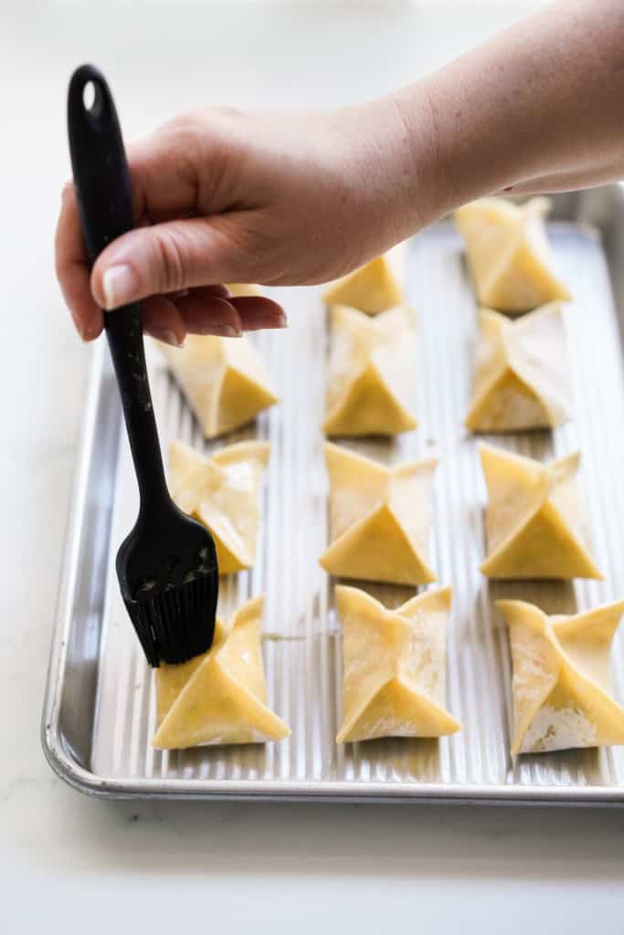 Brushing crab rangoons with egg wash