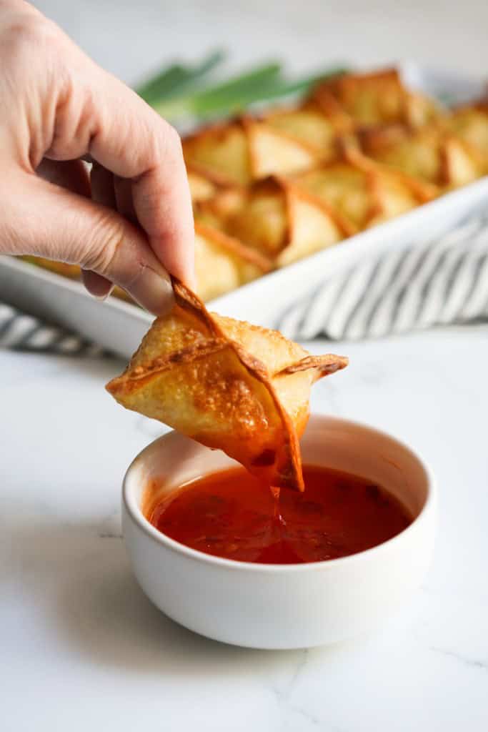 Dipping a crab rangoon into sweet chili sauce