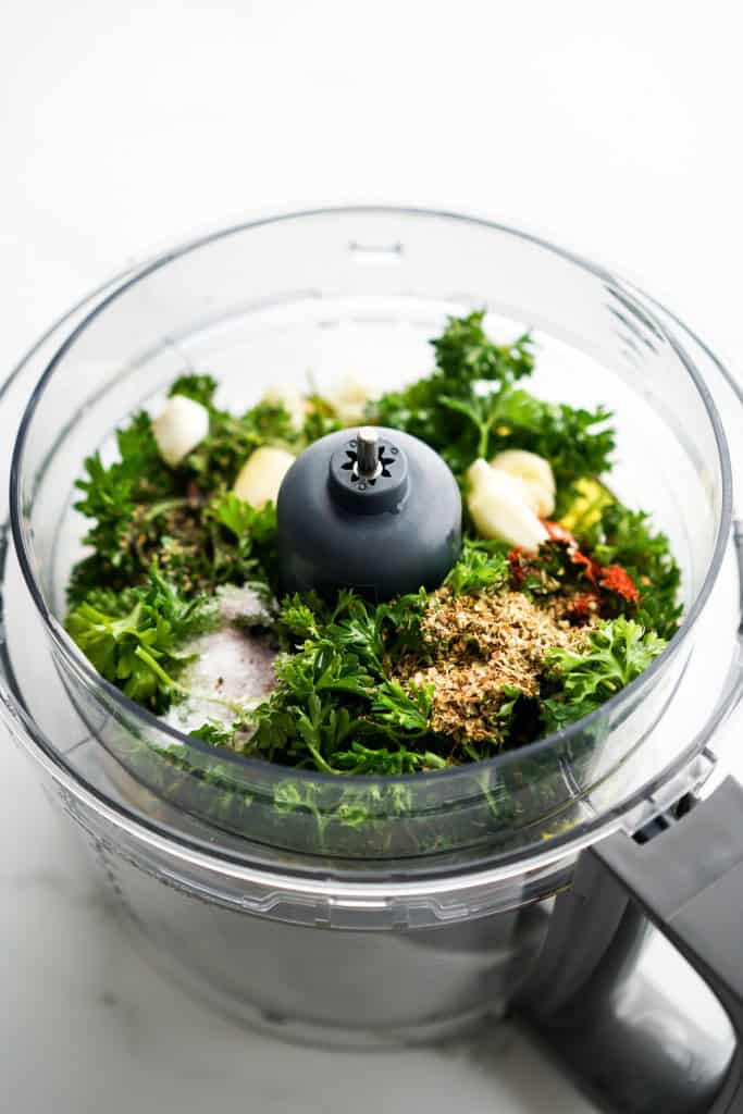 Parsley, garlic cloves, red pepper flakes, olive oil, oregano, paprika in a food processor before pulsing