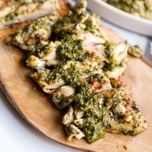 Grilled chimichurri marinated chicken topped with more chimichurri sauce on a wood platter