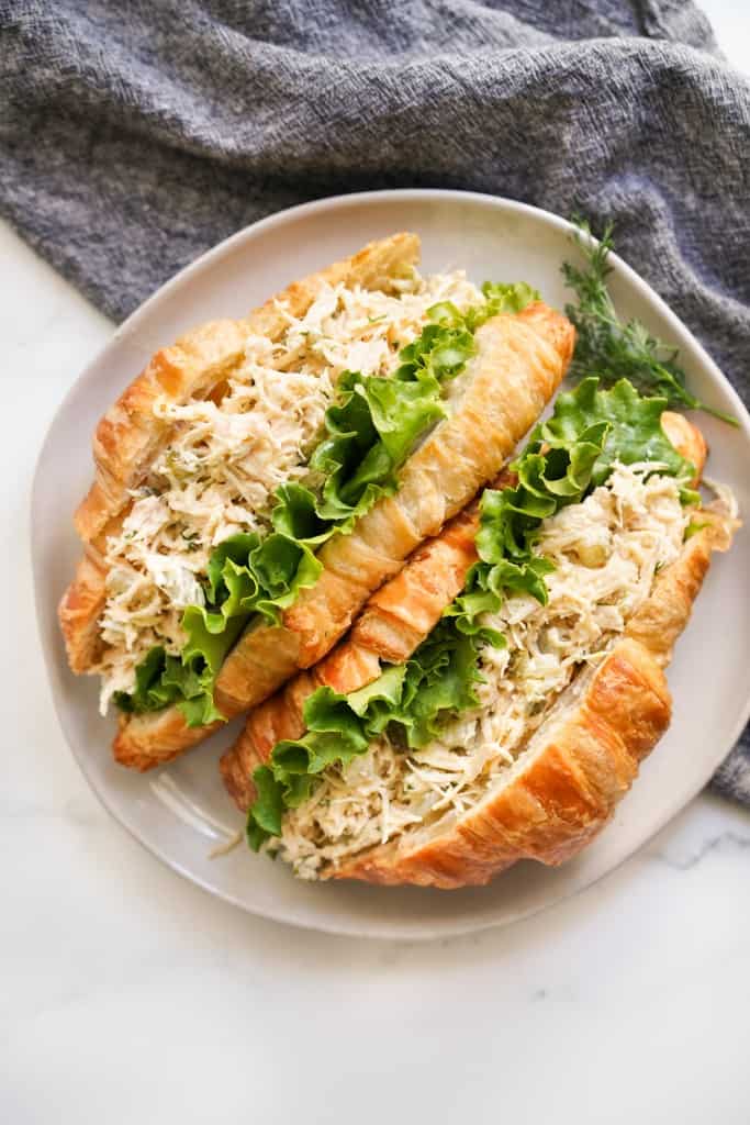 Two croissants stuffed with chicken salad loaded with pickles