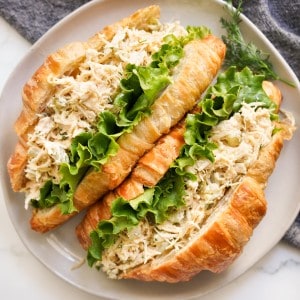 Two croissants stuffed with lettuce and dill pickle chicken salad