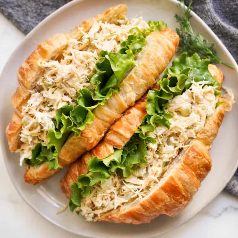 Two croissants stuffed with lettuce and dill pickle chicken salad