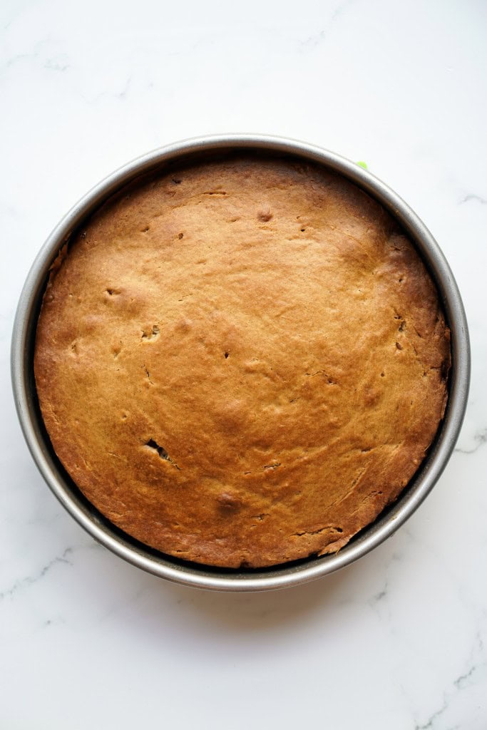 Fully baked peach upside down cake in a metal cake pan, prior to being inverted upside down