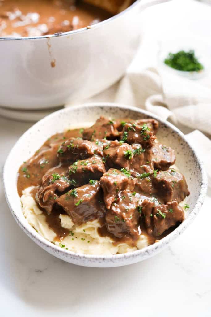A bowl of mashed potatoes topped with beef tips and gravy