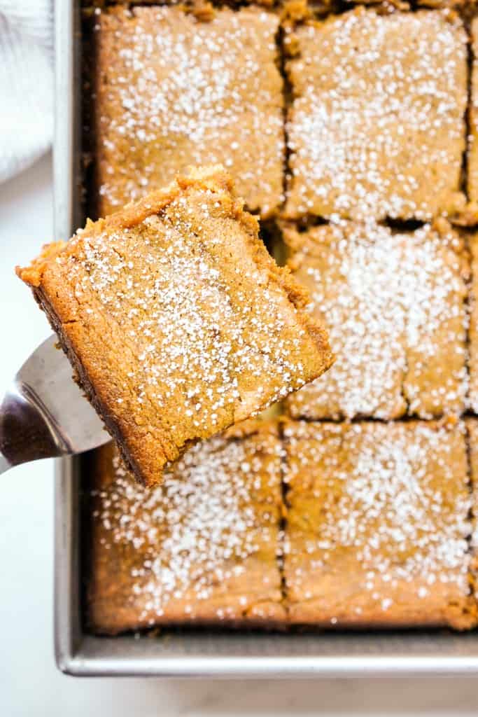 Lifting up a slice of pumpkin chess squares from a baking pan