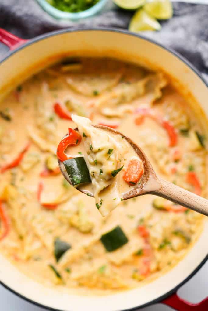 Lifting up a dumpling from a pot of Thai red curry dumpling soup