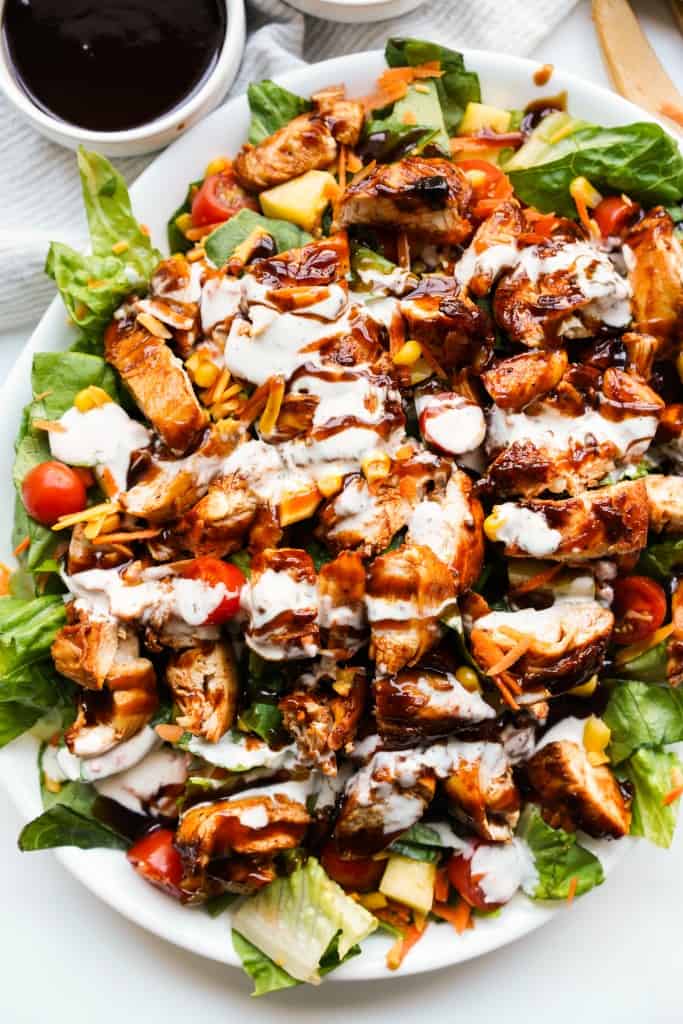 A large platter of bbq chicken salad drizzled with  buttermilk ranch and bbq sauce.