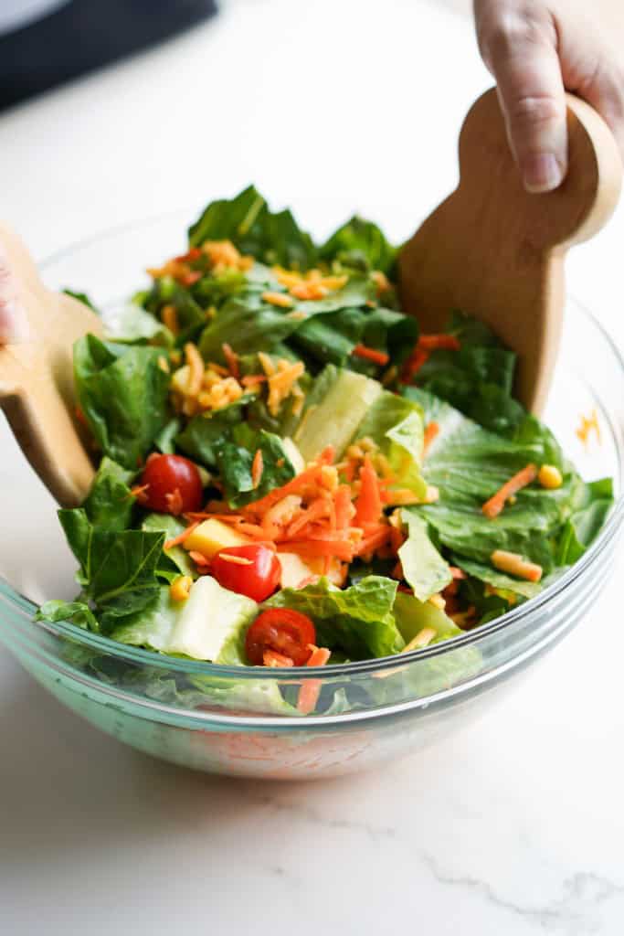 Tossing a bowl of salad using wooden salad spoons