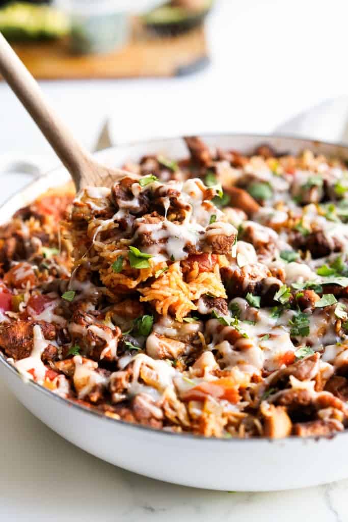 Scooping out Mexican chicken and rice from a braiser.