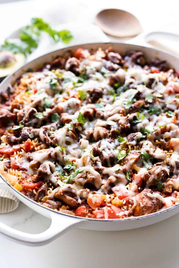 A large braiser loaded with Mexican Chicken and Rice, topped with melted cheese